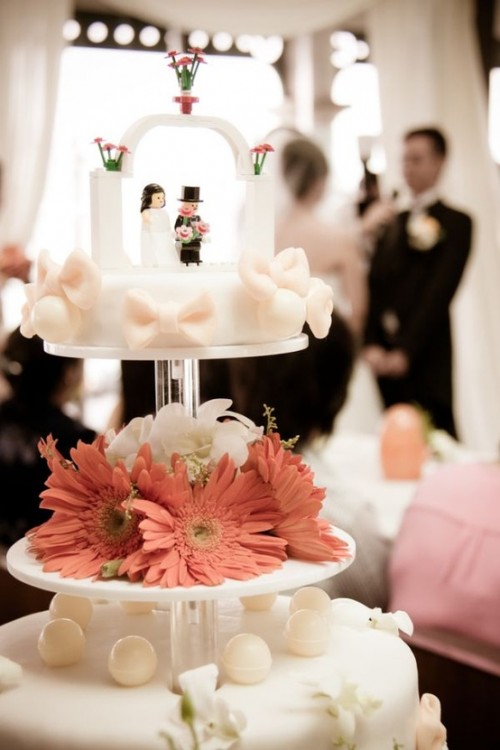 a white bow wedding cake with Lego figurines as cake toppers is a cool idea
