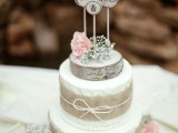 a rustic wedding cake with white textural buttercream, burlap, blooms, a wood slice and wood slice toppers is a cool piece