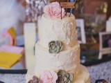 a white textural buttercream wedding cake with sugar flowers and succulents and some wooden toppers is a cool idea