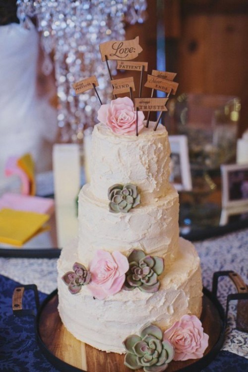 a white textural buttercream wedding cake with sugar flowers and succulents and some wooden toppers is a cool idea