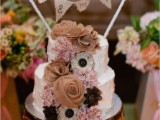 a white textural wedding cake with fabric blooms and a burlap bunting is a cool rustic dessert