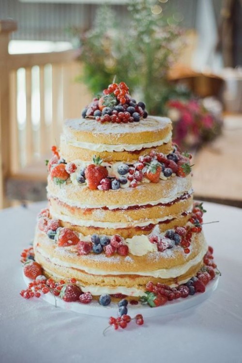 a naked wedding cake with fresh berries and sugar powder is a gorgeous and delicious rustic wedding dessert