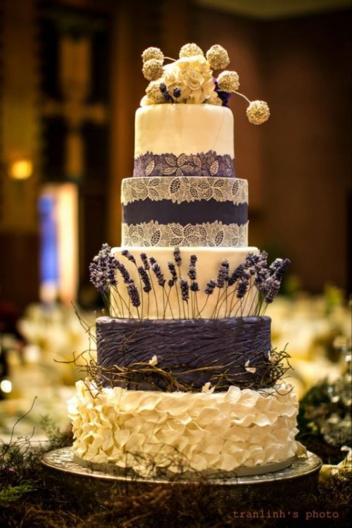 a refined rustic wedding cake in white and purple, with lace, sleek and textural tiers and some lavender and vine