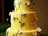 a whimsical yellow rustic wedding cake decorated with white pearls and sugar blooms and topped with bees is a lovely idea