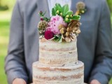 a naked wedding cake with bright blooms and greenery is a nice dessert for a rustic wedding
