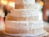 a simple and cool white textural buttercream wedding cake with burlap and white blooms on top is rustic classics