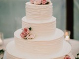 a simple and elegant white buttercream wedding cake with pink and blush blooms is a chic rustic wedding dessert to try