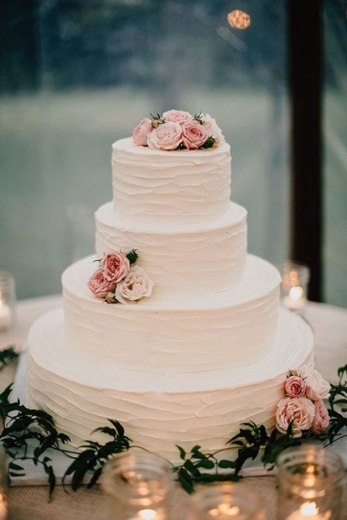 a simple and elegant white buttercream wedding cake with pink and blush blooms is a chic rustic wedding dessert to try