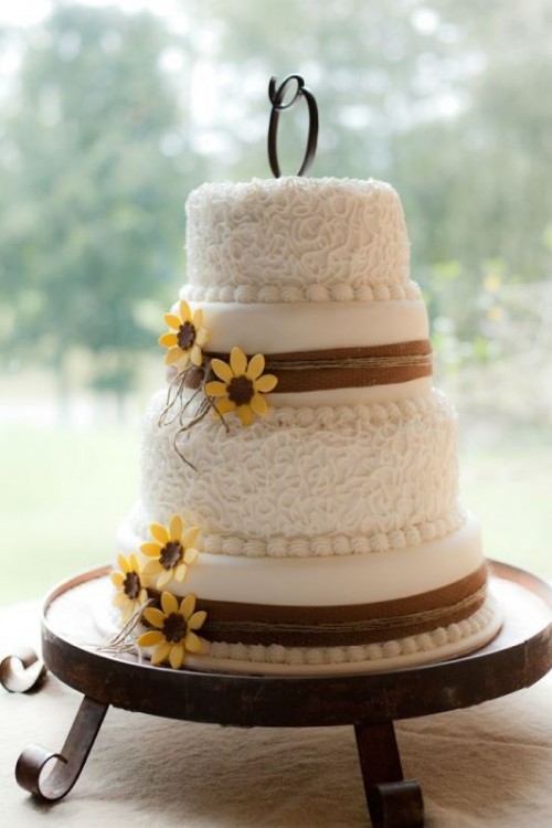 a white patterned and sleek wedding dessert with brown burlap ribbons and sugar blooms plus a monogram topper