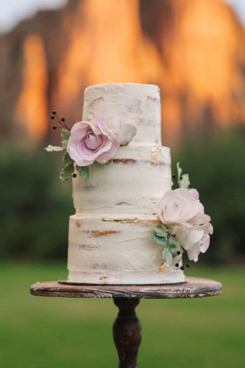 a naked wedding cake with gold leaf and pink blooms and greenery is a lovely idea for any rustic wedding