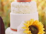 a white lace and patterned wedding cake with burlap, sunflowers and lace for a rustic chic wedding