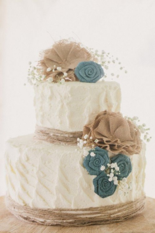 a white textural buttercream wedding cake with fabric blooms and baby's breath is a lovely rustic wedding idea