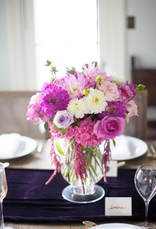 a purple velvet wedding table runner beautifully pairs with hot pink and fuchsia blooms of the centerpiece and they look amazing together