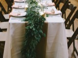 a lush greenery table dotted with some white blooms here and there for a more elegant and chic look