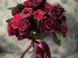 a refined wedding bouquet of red and marsala roses with a matching ribbon is a timeless idea for many weddings