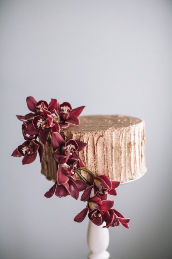 A gold wedding cake with plenty of texture and marsala blooms is a refined and beautiful dessert to rock