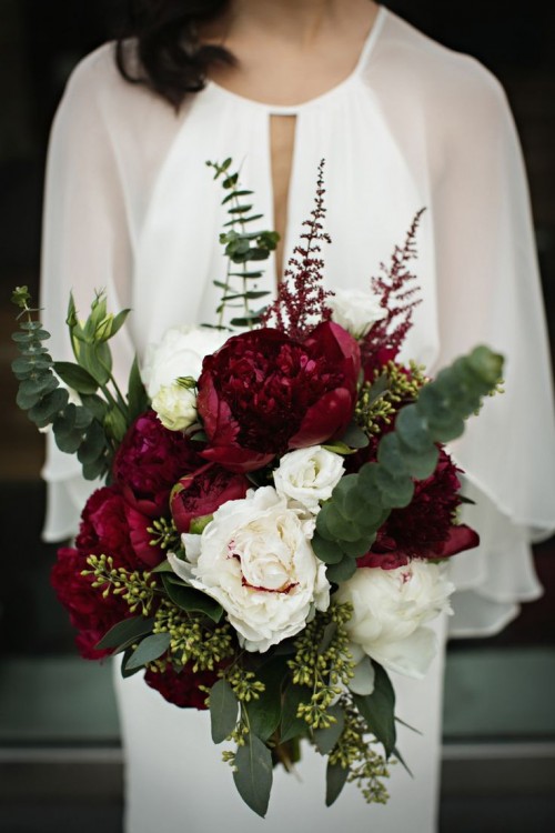 a beautiful dimnesional wedding bouquet of marsala, white blooms and creative and textural greenery and foliage