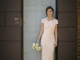 a blush minimalist sheath wedding dress with a geometric neckline, short sleeves and a train is romantic