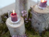 a woodland wedding centerpiece of moss, tree stumps, candles and blooms is a catchy and cool idea for a wedding