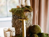 a cool woodland wedding centerpiece of a tree stump, moss balls, pillar candles and a monogram is a cool solution