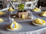 a box with greenery and yellow blooms is a nice and cute barn wedding centerpiece