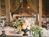 a black urn with pastel and neutral blooms plus cascading textural greenery is a very elegant wedding centerpiece