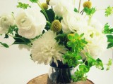 a wood slice with a jar wrapped with yarn, white blooms and greenery plus billy balls is a cool decoration