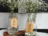 clear jars with baby’s breath and tags are cool and simple barn wedding centerpieces