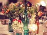 bottles and vases with simple greenery and bright and white blooms plus candles is a combo that works for many weddings including barn ones