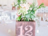 a plywood box with a table number and pastel blooms and greenery is a cool barn wedding centerpiece idea