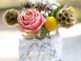 a jar wrapped with lace with pink and yellow blooms and darker ones for a rustic or barn wedding