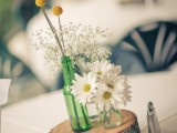 a wood slice with white blooms and billy balls plus a table name is a stylish idea for a wedding centerpiece
