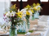 a brigth barn wedding centerpiece of white, pink and yellow blooms and greenery for a rustic wedding