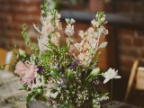 a cozy barn wedding centerpiece of a wooden box and some neutral and pink flowers plus greenery