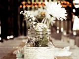 a jar wrapped with yarn and white blooms is a nice centerpiece for a cool barn wedding