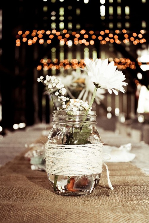 a jar wrapped with yarn and white blooms is a nice centerpiece for a cool barn wedding