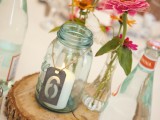 a candle in a har with a tag, a wood slice and some bright pink blooms for a barn wedding centerpiece