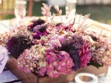 a bright fall wedding centerpiece of pink and purple blooms and herbs is a stylish idea for a barn wedding