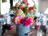 a galvanized bucket with bright blooms and greenery is a cool rustic option to go for