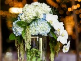 a clear glass vase with greenery and white and blue blooms plus white orchids for a quirky look