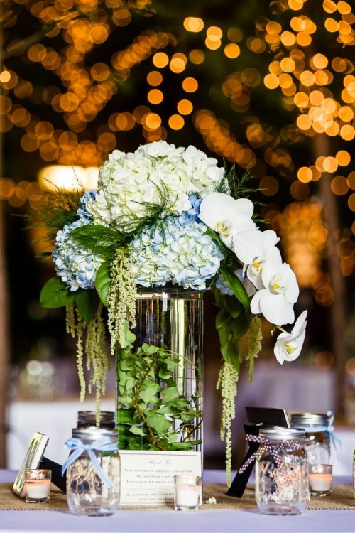a clear glass vase with greenery and white and blue blooms plus white orchids for a quirky look