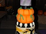 a Halloween wedding cake with a purple, orange pumpkin, skull and scary tree tier plus cool sugar toppers and a graveyard at the bottom