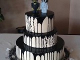 a round white wedding cake with black dripping and scary toppers on top looks spooky and very statement-like