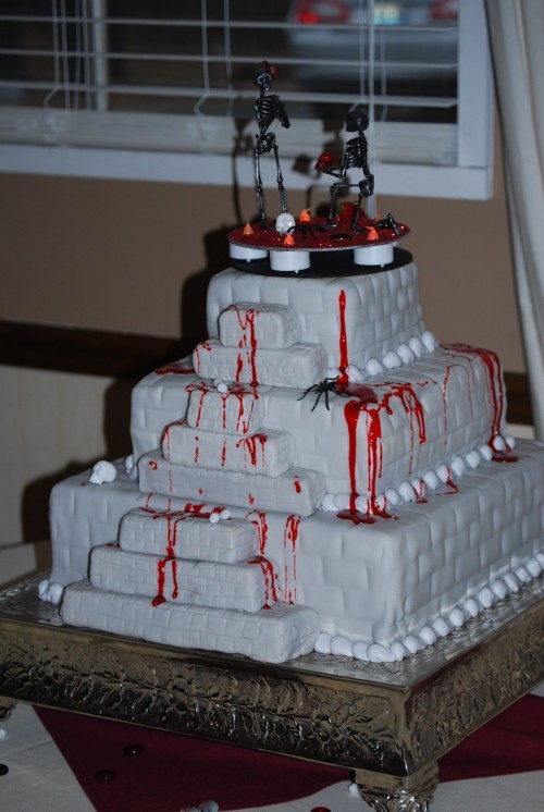 a bloody square buttercream wedding cake with skeletons on top is a nice idea for a Halloween wedding