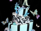a whimsical blue, white and black wedding cake with stripes and patterns, blue flowers and butterflies and Nightmare Before Christmas toppers