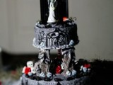 a statement Halloween wedding cake with painting, skulls, candies, an altar and a couple topper