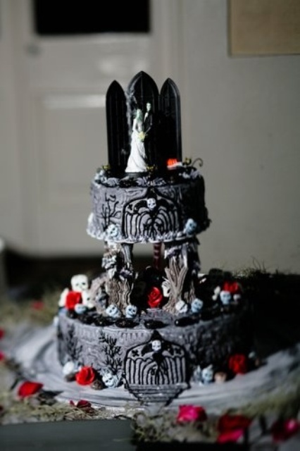 a statement Halloween wedding cake with painting, skulls, candies, an altar and a couple topper