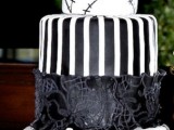 a black and white wedding cake with a striped and lace tier plus some catchy images and large sugar blooms