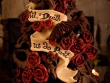 a crazy dark chocolate wedding cake with angels, red roses, ribbons and a quote is a nice and very unusual idea for a Halloween wedding