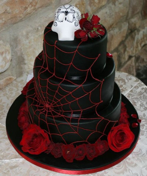 a black and red spiderweb wedding cake with red roses and a sugar skull on top is a stylish idea for Halloween